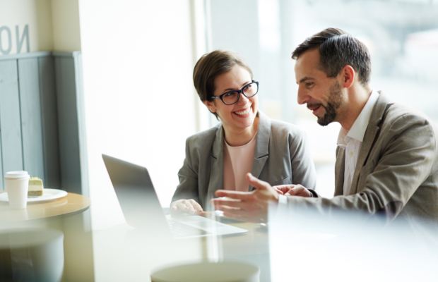 Happy economists sitting in cafe and discussing online financial news